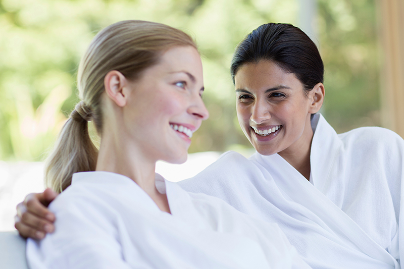 Happy women friends in bathrobes relaxing in spa